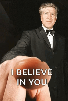 A Man In A Tuxedo Is Being Held Up By A Finger That Says I Believe In You GIF