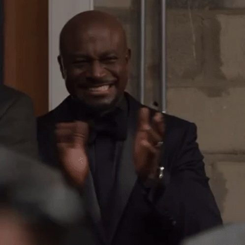 A Man In A Tuxedo Is Clapping His Hands And Making A Funny Face . GIF