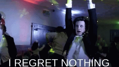 A Man In A Tuxedo Is Dancing With His Arms In The Air And The Words I Regret Nothing Below Him . GIF