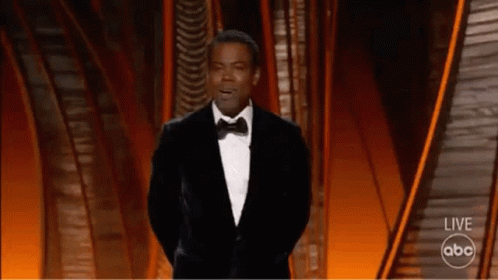 A Man In A Tuxedo Is Giving A Speech On A Stage . GIF