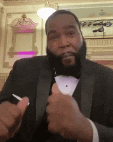 A Man In A Tuxedo Is Giving A Thumbs Up Sign GIF