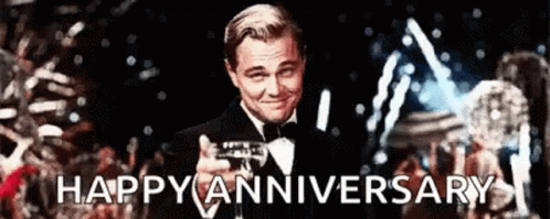 A Man In A Tuxedo Is Holding A Trophy And The Words Happy Anniversary Are Behind Him GIF
