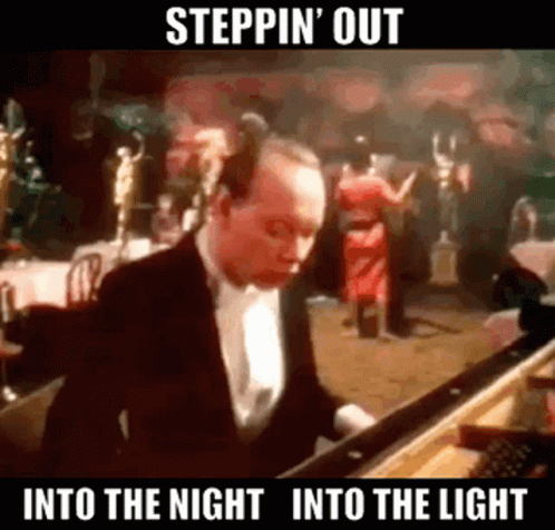 A Man In A Tuxedo Is Playing A Piano In Front Of A Crowd . GIF