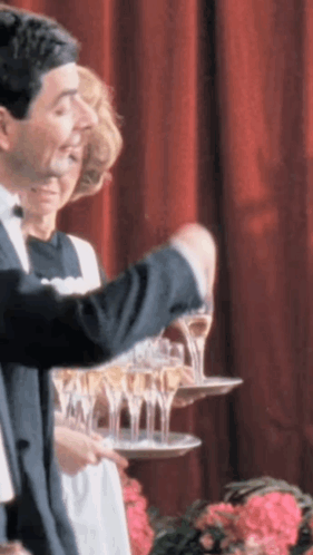 A Man In A Tuxedo Is Pouring Champagne Into A Tray GIF
