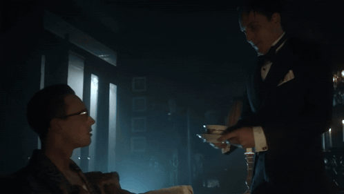 A Man In A Tuxedo Is Serving A Man In A Suit GIF