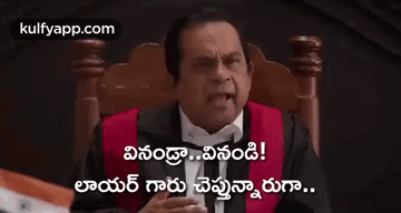 a man in a tuxedo is sitting in a chair holding a gavel and giving a thumbs up .