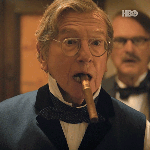 A Man In A Tuxedo Is Smoking A Cigar With The Hbo Logo In The Corner GIF