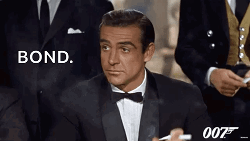 A Man In A Tuxedo Is Smoking A Cigarette And Says Bond GIF