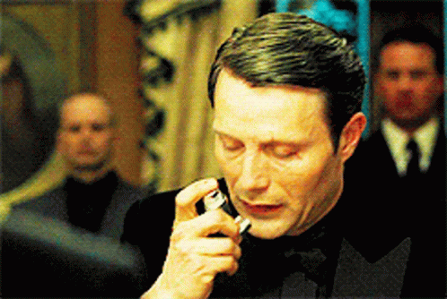 A Man In A Tuxedo Is Smoking A Cigarette In A Room GIF