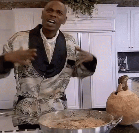 A Man In A Tuxedo Is Standing In A Kitchen Next To A Pot Of Food And A Pumpkin . GIF