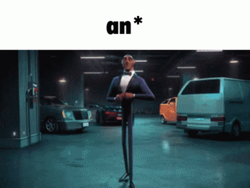 A Man In A Tuxedo Is Standing In A Parking Garage With Cars And The Word An * Above Him GIF