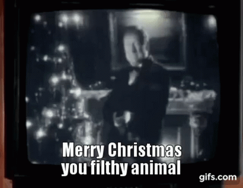 A Man In A Tuxedo Is Standing In Front Of A Christmas Tree On A Tv Screen . GIF