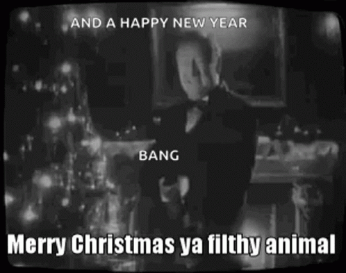 A Man In A Tuxedo Is Standing In Front Of A Christmas Tree With The Words Merry Christmas Ya Filthy Animal . GIF