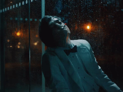 A Man In A Tuxedo Is Standing In Front Of A Window GIF