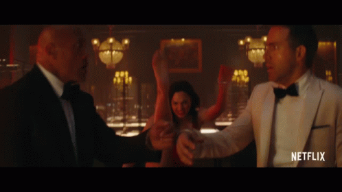 A Man In A Tuxedo Is Standing Next To A Woman In A Red Dress And A Man In A White Suit GIF