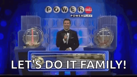A Man In A Tuxedo Is Standing On A Stage In Front Of A Powerball Lottery Machine . GIF