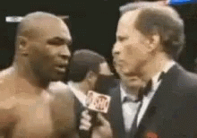 A Man In A Tuxedo Is Talking To A Boxer . GIF
