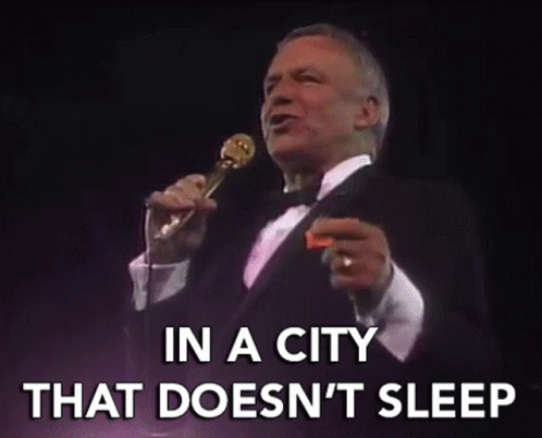 a man in a tuxedo singing into a microphone with the words in a city that does n't sleep