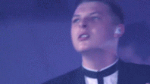 A Man In A Tuxedo Sings Into A Microphone In Front Of A Drum Set That Has The Letter N On It GIF