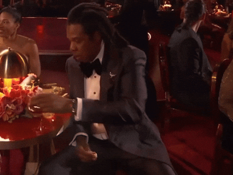 A Man In A Tuxedo Sits At A Table GIF