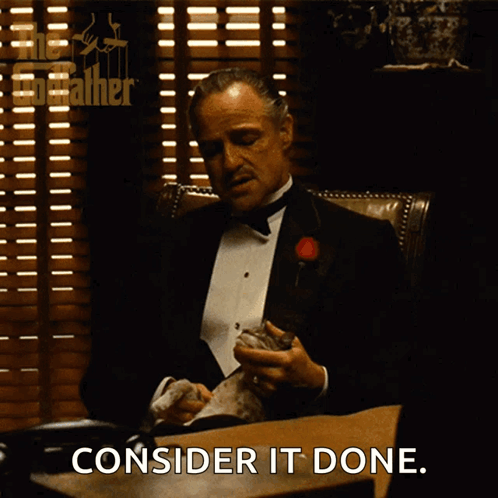 A Man In A Tuxedo Sitting At A Desk With The Words Consider It Done Written Below Him GIF