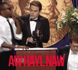 A Man In A Tuxedo Stands At A Podium With Aw Hayl Naw Written On It GIF
