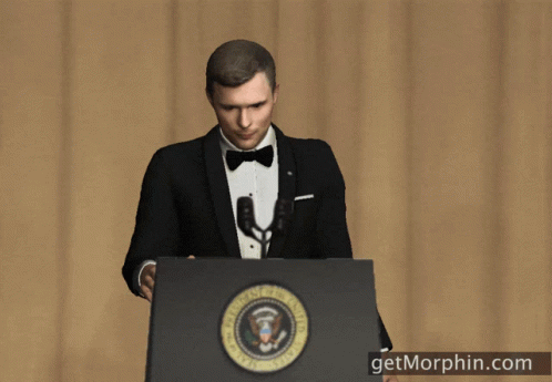 A Man In A Tuxedo Stands At A Podium With The Seal Of The President Of The United States GIF