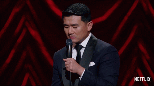 a man in a tuxedo stands in front of a microphone with netflix written on the bottom