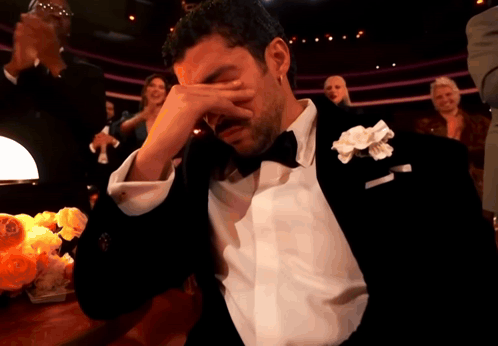 A Man In A Tuxedo With A White Flower In His Lapel Is Crying GIF