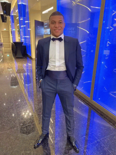 A Man In A Tuxedo With His Hands In His Pockets Stands In Front Of A Wall That Says ' The ' On It GIF
