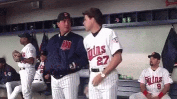 A Man In A Twins Jersey Talks To Another Man In A Dugout GIF