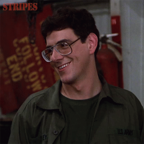 A Man In A U.s. Army Uniform Is Smiling And Wearing Glasses GIF