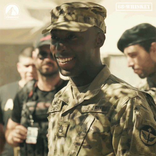 a man in a u.s. army uniform smiles in front of a sign that says 68 whiskey