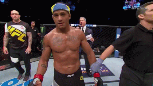 A Man In A Ufc Shirt Is Standing In A Boxing Ring GIF