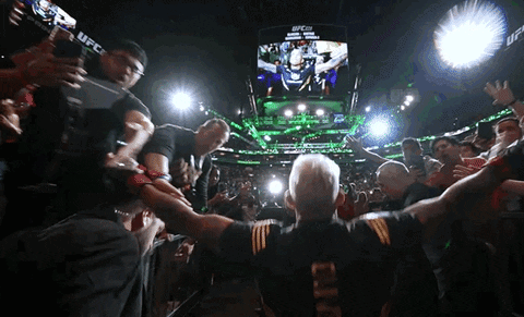 a man in a ufc shirt stands in front of a crowd of people