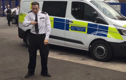 A Man In A Uniform Stands In Front Of A White Van That Says Newcastle Police GIF