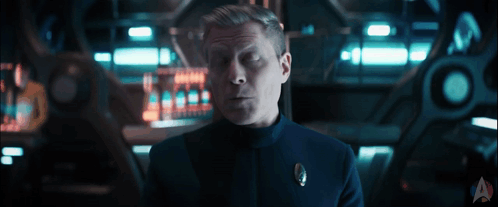 A Man In A Uniform With A Star Trek Logo On The Bottom Right GIF
