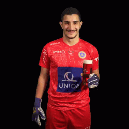 a man in a uniqa jersey holds up a glass of beer