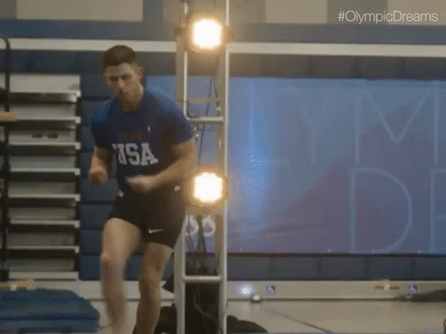 A Man In A Usa Shirt Jumps In The Air GIF