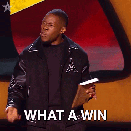 A Man In A Varsity Jacket Is Holding A Piece Of Paper And Says What A Win GIF