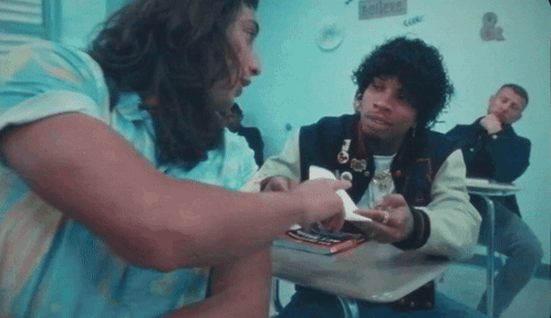 A Man In A Varsity Jacket Is Talking To Another Man In A Blue Shirt GIF