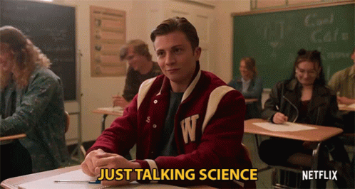 A Man In A Varsity Jacket With The Letter W On It Sits In A Classroom GIF