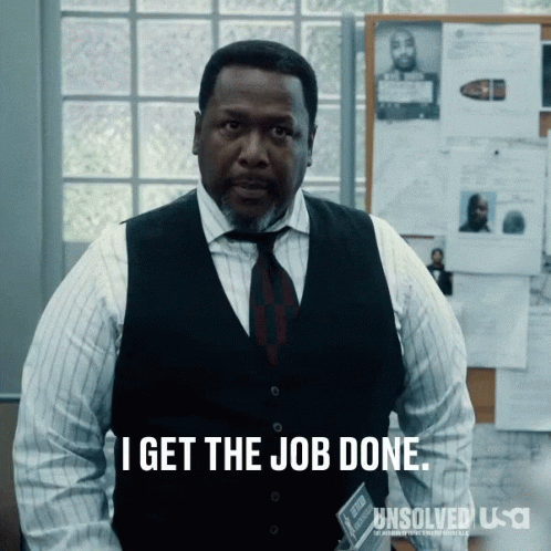 A Man In A Vest And Tie Is Standing In Front Of A Bulletin Board That Says I Get The Job Done GIF