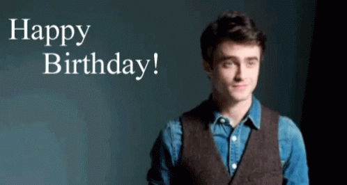 A Man In A Vest Is Standing In Front Of A Sign That Says Happy Birthday ! GIF