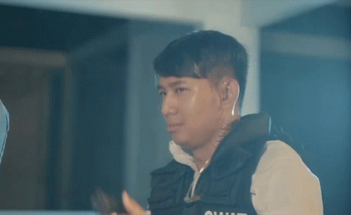 a man in a vest with the word squad on it holds a gun