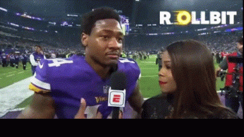 A Man In A Vikings Jersey Is Talking Into A Microphone GIF