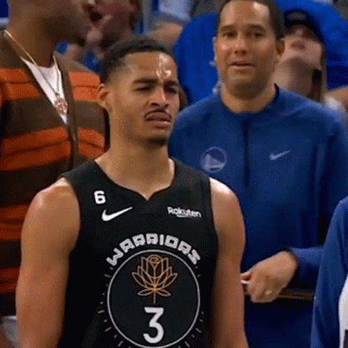 a man in a warriors jersey stands in a crowd