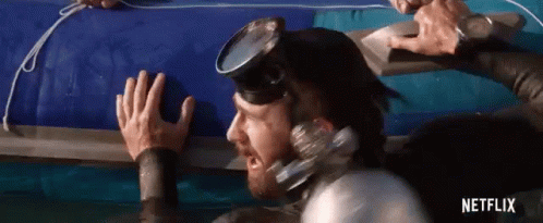 A Man In A Wet Suit And Goggles Is Reaching For A Raft . GIF
