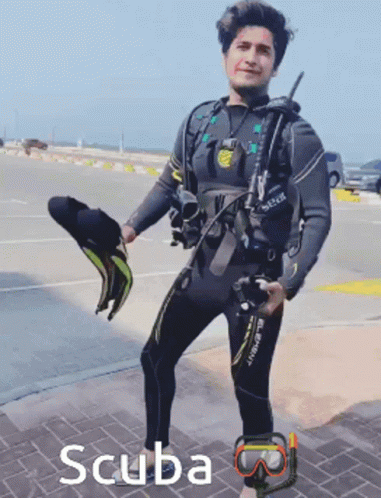 A Man In A Wetsuit Is Holding A Pair Of Scuba Masks GIF