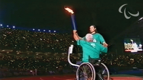 a man in a wheelchair is being helped by a woman holding a fire torch